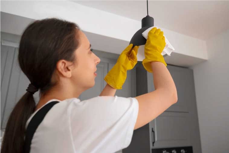 Woman cleaning a lamp in an Airbnb space