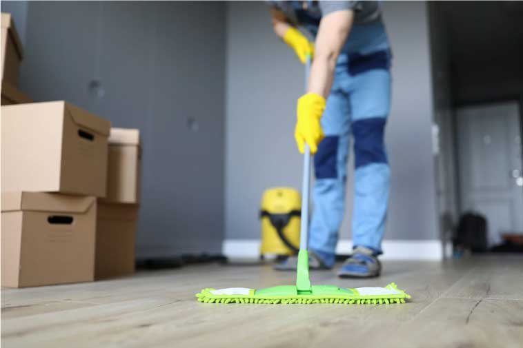 Man cleaning a floor with moving boxes on one side