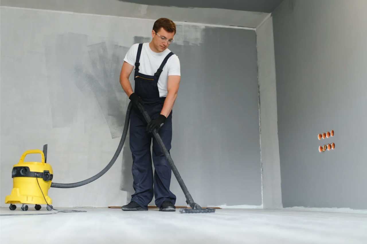 Man using a vacuum cleaner in a room under construction